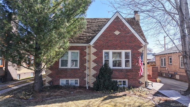 view of front facade featuring brick siding and a chimney