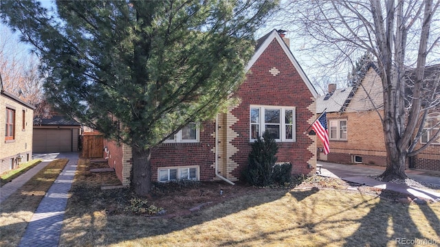 tudor home featuring brick siding, an outdoor structure, and a detached garage