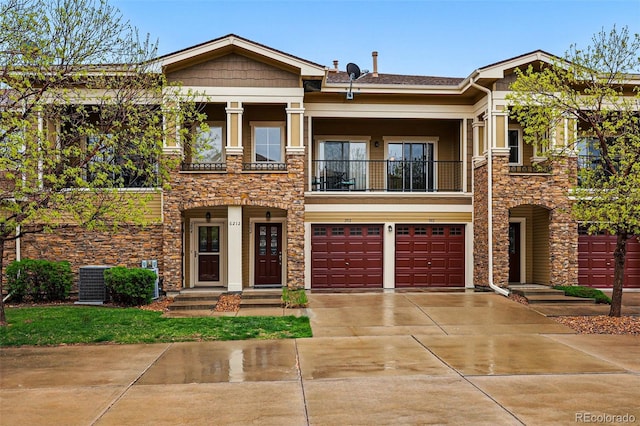 view of front facade featuring stone siding, concrete driveway, a balcony, a garage, and cooling unit