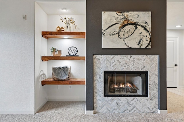 detailed view of carpet floors, baseboards, and a fireplace