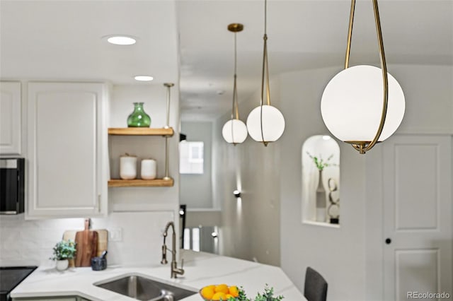 kitchen featuring a sink, stainless steel microwave, light countertops, open shelves, and white cabinets