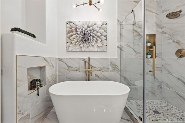 bathroom featuring marble finish flooring, a shower stall, a freestanding tub, and tile walls