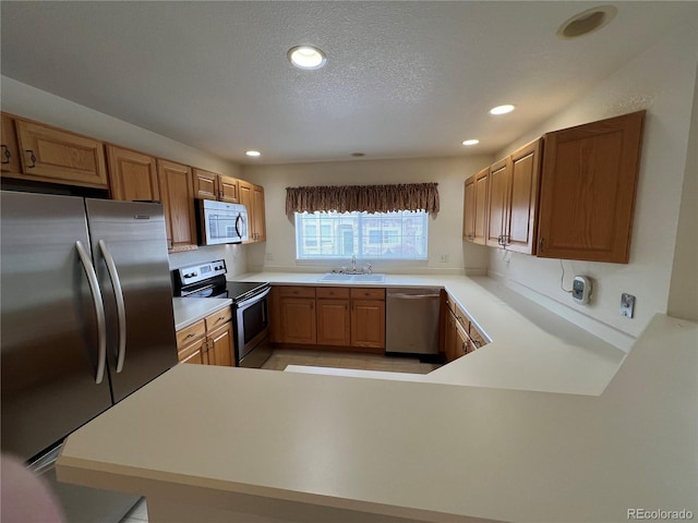 kitchen featuring sink, kitchen peninsula, a textured ceiling, and stainless steel appliances