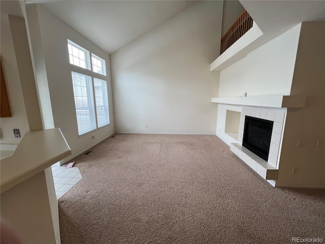 unfurnished living room featuring light carpet, high vaulted ceiling, and a tile fireplace