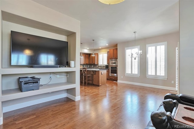 living room featuring wood finished floors, a chandelier, and baseboards