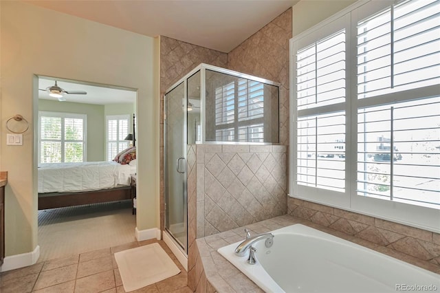 ensuite bathroom with a shower stall, a garden tub, a ceiling fan, and baseboards