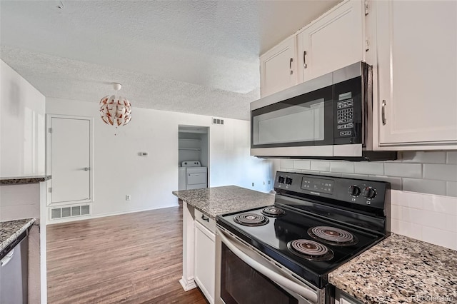 kitchen featuring white cabinets, dark stone counters, and black electric range