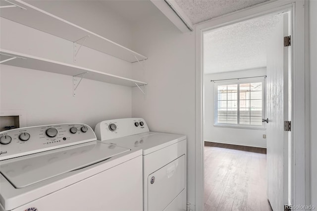 laundry area with hardwood / wood-style floors, a textured ceiling, and washing machine and clothes dryer