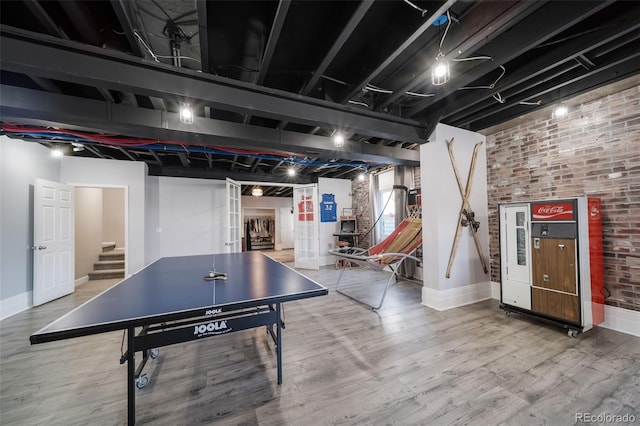 game room featuring brick wall and hardwood / wood-style floors