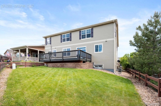 rear view of house with cooling unit, a deck, and a lawn