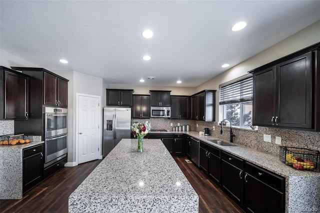 kitchen with dark hardwood / wood-style floors, tasteful backsplash, sink, light stone counters, and stainless steel appliances