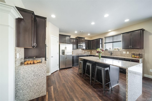 kitchen featuring dark wood-type flooring, sink, a breakfast bar area, appliances with stainless steel finishes, and a kitchen island