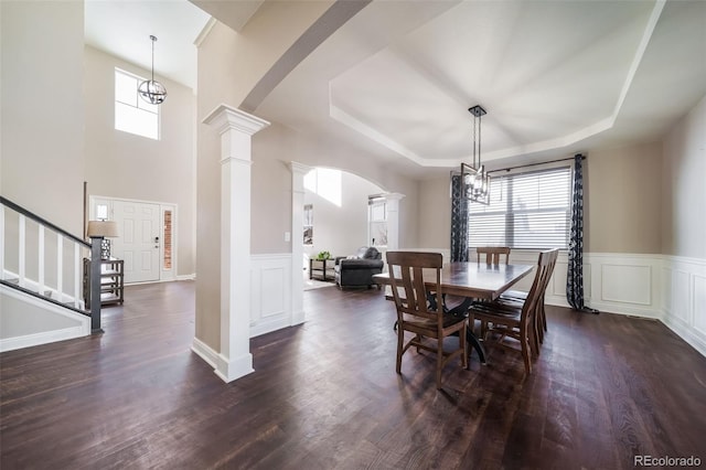 dining room featuring a chandelier, a tray ceiling, dark hardwood / wood-style flooring, and decorative columns