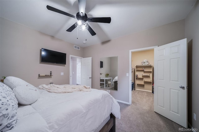 carpeted bedroom with a walk in closet, ceiling fan, and a closet