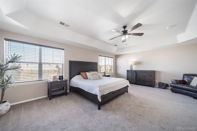 carpeted bedroom featuring ceiling fan and a tray ceiling