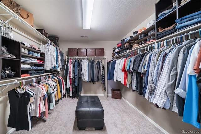 walk in closet with light carpet