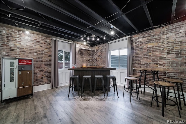 bar with hardwood / wood-style floors, rail lighting, white cabinets, and brick wall