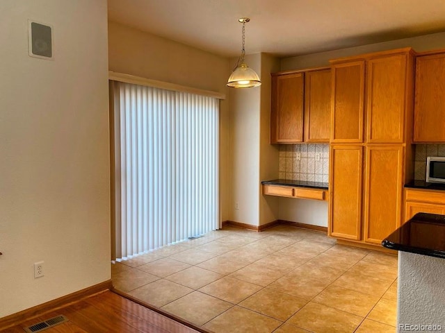 1022 Morning Dove Dr, Longmont, CO 80504 - kitchen featuring backsplash, pendant lighting, brown cabinets, stainless steel microwave, and baseboards