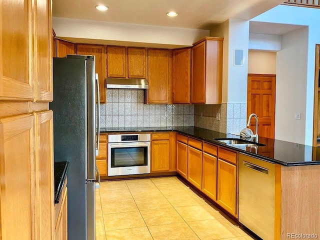 1022 Morning Dove Dr, Longmont, CO 80504 - kitchen with stainless steel appliances, a sink, under cabinet range hood, a peninsula, and decorative backsplash