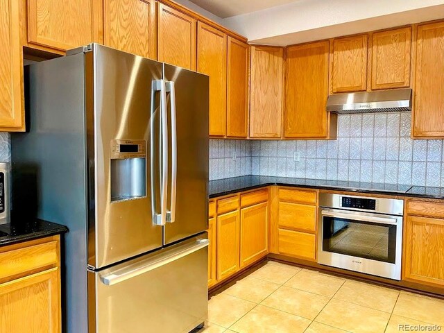 1022 Morning Dove Dr, Longmont, CO 80504 - kitchen featuring appliances with stainless steel finishes, under cabinet range hood, light tile patterned floors, and backsplash