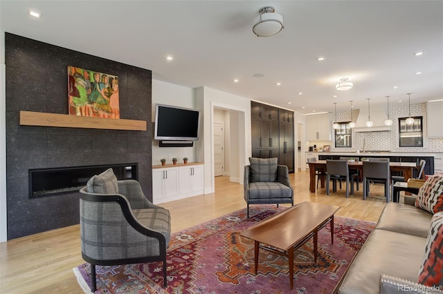 living room featuring a tile fireplace and light hardwood / wood-style flooring