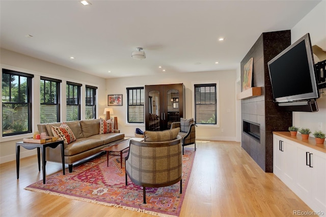 living room with a tiled fireplace, a wealth of natural light, and light hardwood / wood-style floors