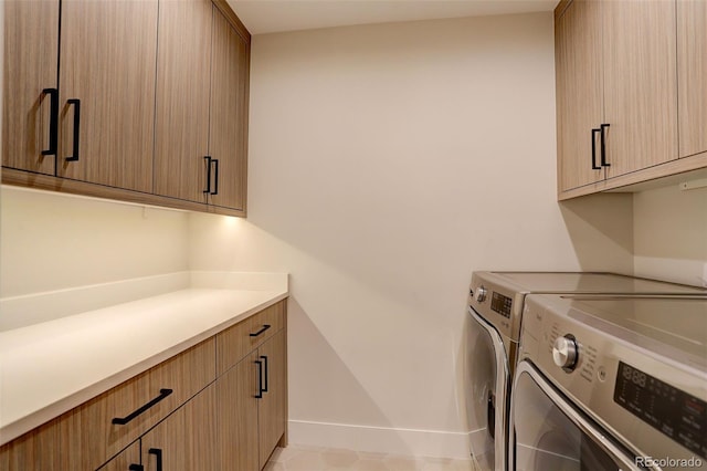 clothes washing area with cabinets and washing machine and dryer