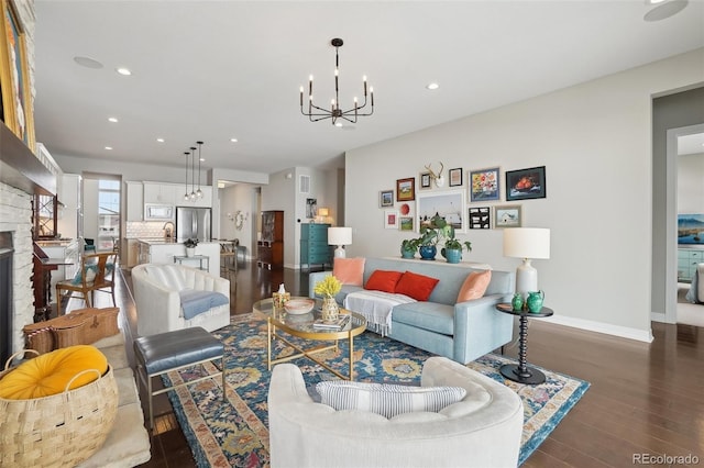 living area with a fireplace, recessed lighting, an inviting chandelier, dark wood-type flooring, and baseboards