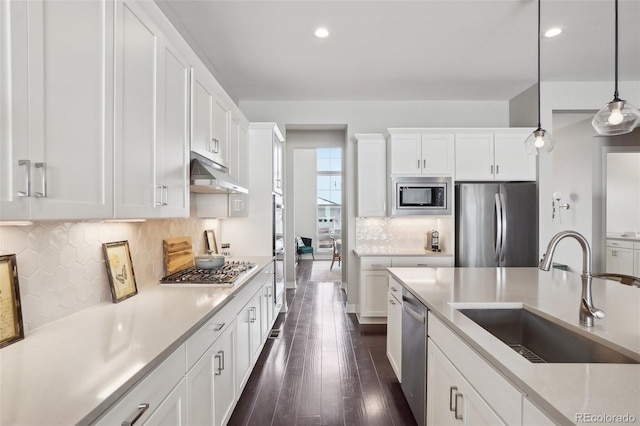 kitchen with under cabinet range hood, a sink, white cabinets, light countertops, and appliances with stainless steel finishes