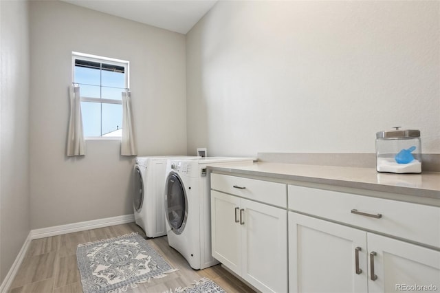 laundry area featuring cabinet space, light wood-style flooring, baseboards, and washing machine and clothes dryer