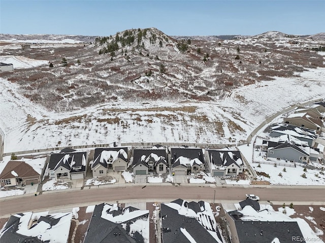 snowy aerial view featuring a residential view and a mountain view