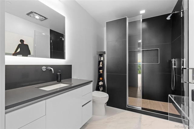 bathroom with a tile shower, vanity, and toilet