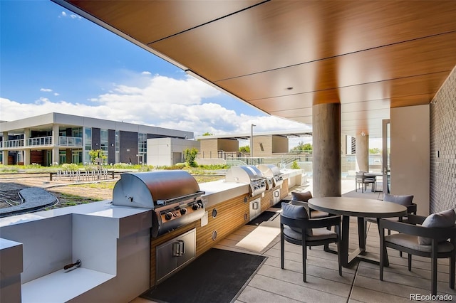 view of patio with an outdoor kitchen, a balcony, and a grill