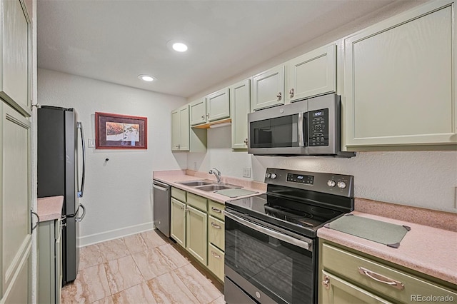 kitchen with appliances with stainless steel finishes, marble finish floor, light countertops, a sink, and green cabinetry