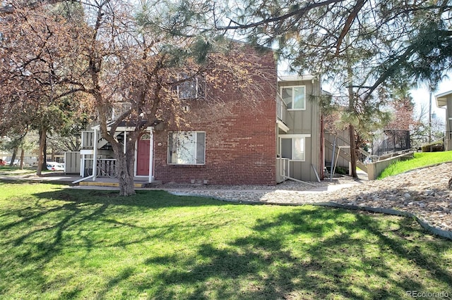 back of property with a yard, stairway, brick siding, and central AC unit