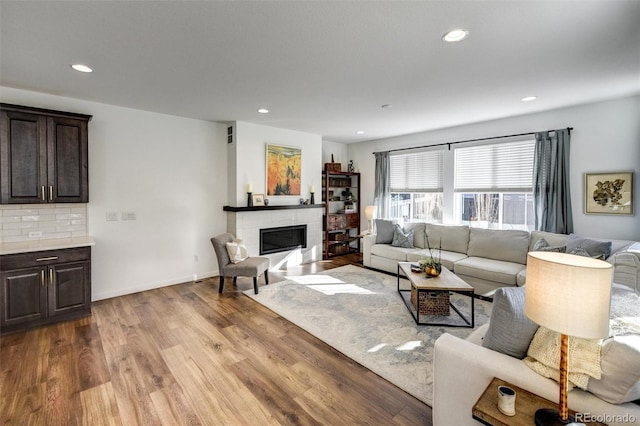 living room featuring a tiled fireplace and light wood-type flooring