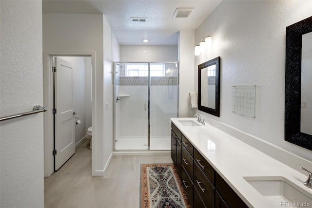 bathroom featuring a textured ceiling, walk in shower, vanity, and toilet