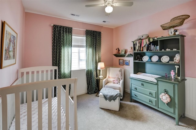 bedroom with radiator, a nursery area, light carpet, and ceiling fan