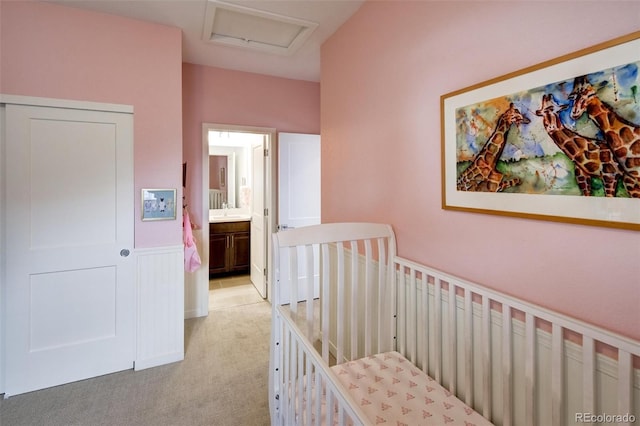 carpeted bedroom with ensuite bath and a nursery area