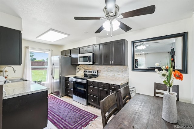 11941 Bellaire St Unit B, Thornton, CO 80233 - kitchen featuring stainless steel appliances, decorative backsplash, light countertops, ceiling fan, and dark cabinetry