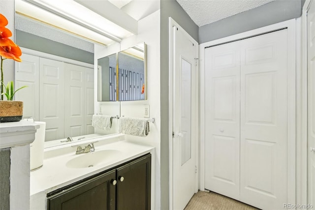 11941 Bellaire St Unit B, Thornton, CO 80233 - bathroom with a closet, vanity, and a textured ceiling