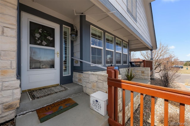 doorway to property with covered porch and stone siding