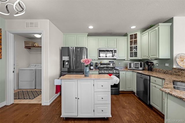 kitchen with dark wood-style flooring, visible vents, appliances with stainless steel finishes, and washing machine and clothes dryer