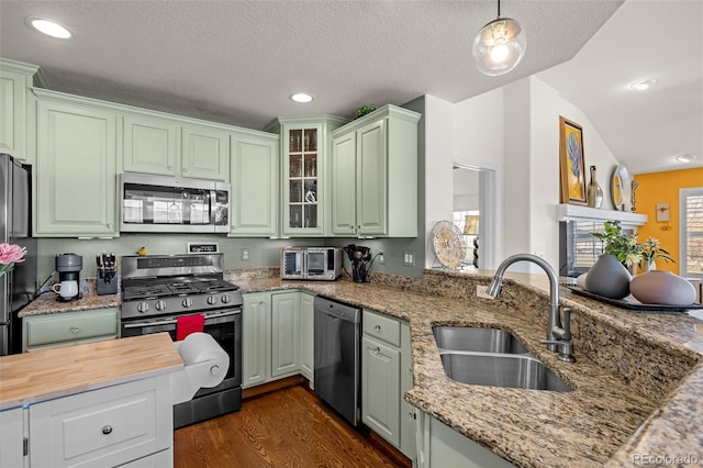 kitchen featuring a sink, green cabinetry, appliances with stainless steel finishes, and dark wood-style floors