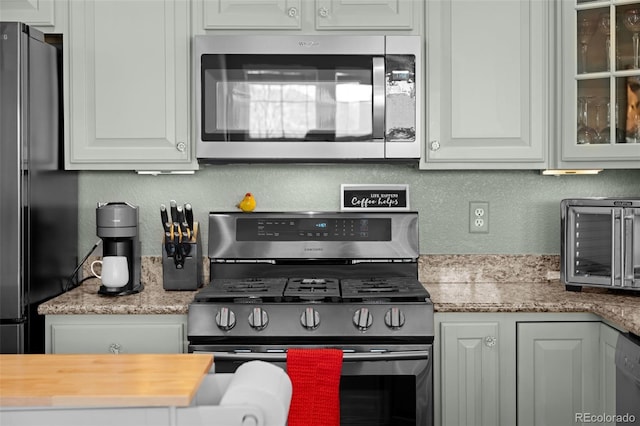 kitchen featuring white cabinets, glass insert cabinets, appliances with stainless steel finishes, and a textured wall