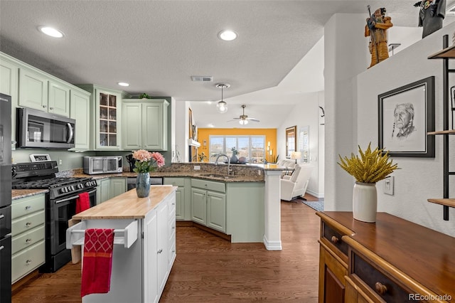 kitchen featuring black gas range, wood counters, stainless steel microwave, a peninsula, and green cabinetry