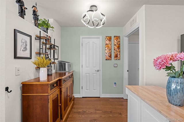 interior space with visible vents, baseboards, an inviting chandelier, and dark wood-style flooring