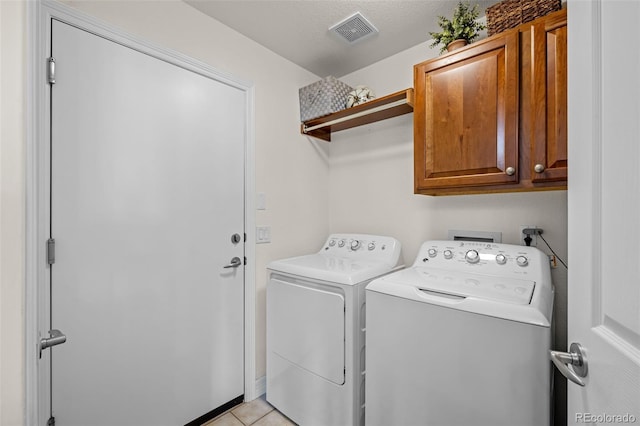 laundry room featuring light tile patterned floors, visible vents, cabinet space, and separate washer and dryer