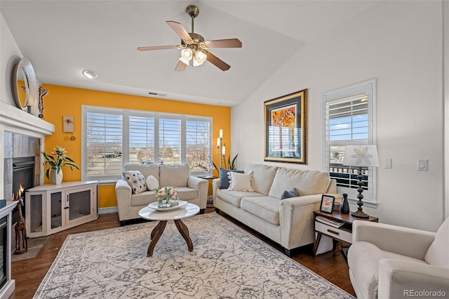 living room with plenty of natural light, a tile fireplace, a ceiling fan, and lofted ceiling