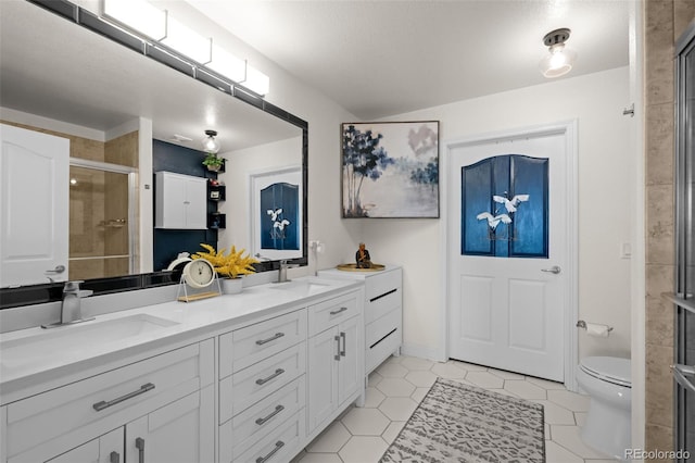 bathroom featuring double vanity, a stall shower, toilet, and a sink